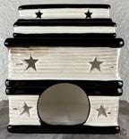 A small ceramic wax warmer with a tiered stack of books showing the pages with star cutouts, and a round entrance hole, shown against a neutral textured background.